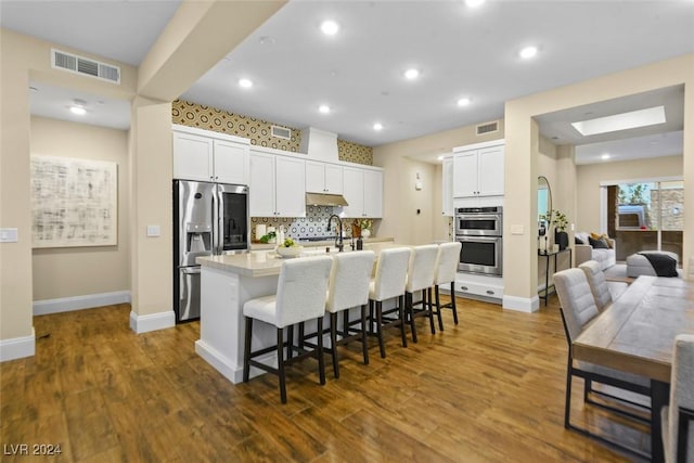 kitchen with visible vents, appliances with stainless steel finishes, a breakfast bar, and decorative backsplash