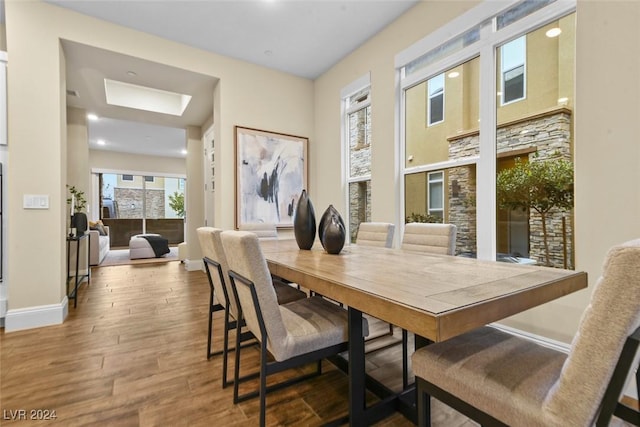 dining area with a skylight, baseboards, and wood finished floors