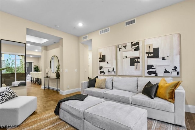 living room featuring baseboards, visible vents, and wood finished floors