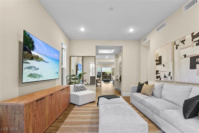 living room with recessed lighting, visible vents, and wood finished floors