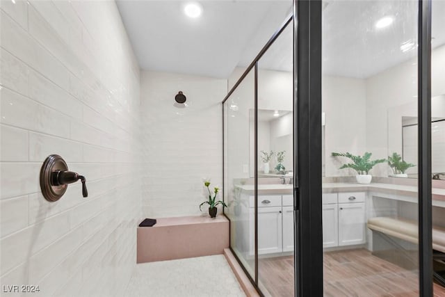 full bath featuring a shower with door, vanity, and wood finished floors