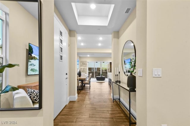 corridor with recessed lighting, wood finished floors, visible vents, baseboards, and a raised ceiling