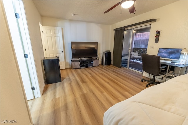 living room featuring light wood-type flooring, a textured ceiling, and ceiling fan