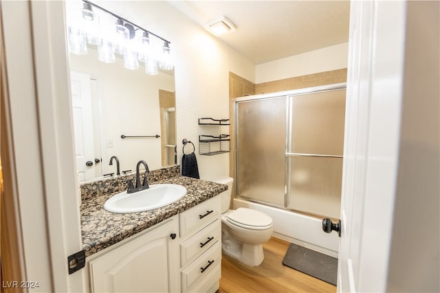 full bathroom with shower / bath combination with glass door, wood-type flooring, vanity, and toilet