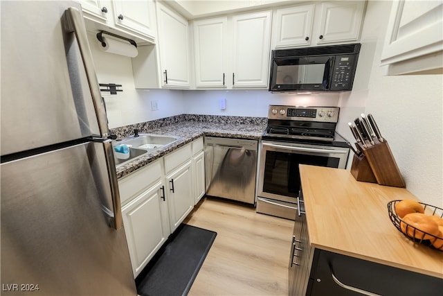 kitchen with white cabinets, appliances with stainless steel finishes, and light hardwood / wood-style floors