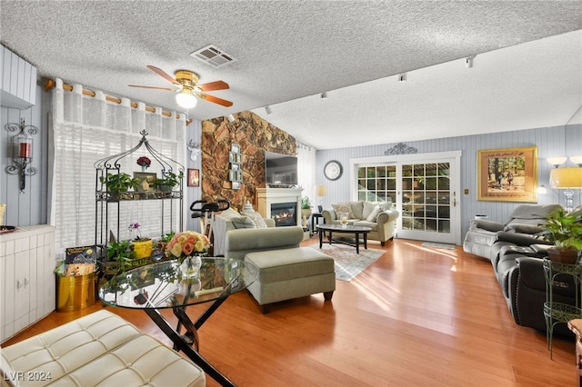 living room featuring a textured ceiling, light hardwood / wood-style floors, ceiling fan, and vaulted ceiling