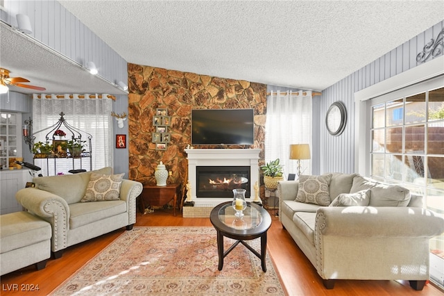 living room featuring lofted ceiling, a textured ceiling, hardwood / wood-style flooring, and a large fireplace