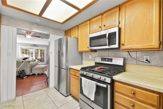 kitchen featuring backsplash, ceiling fan, light wood-type flooring, and appliances with stainless steel finishes