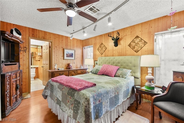 bedroom featuring a textured ceiling, ensuite bath, and multiple windows