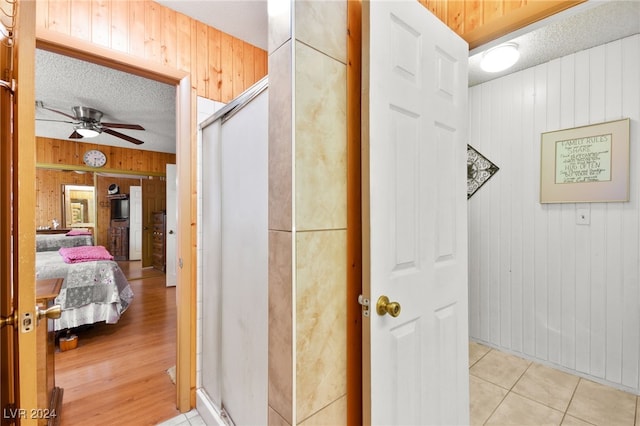 bathroom with hardwood / wood-style floors, ceiling fan, wood walls, and a textured ceiling