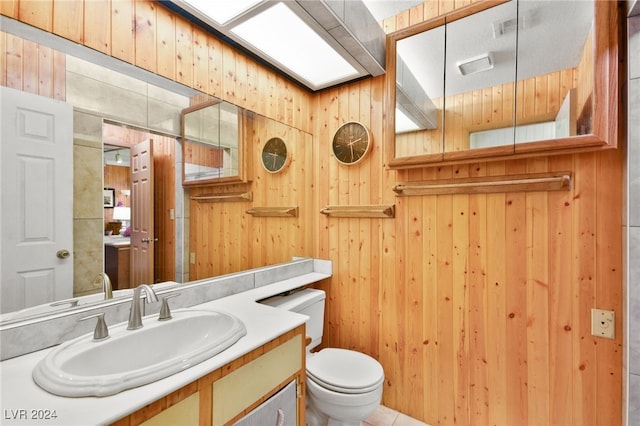 bathroom featuring toilet, vanity, and wooden walls