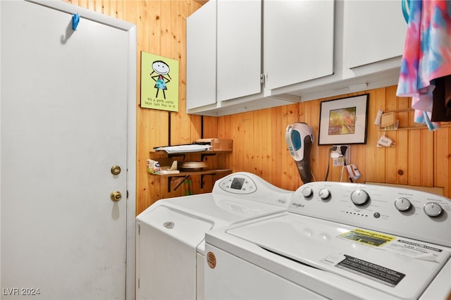 clothes washing area featuring cabinets, wooden walls, and independent washer and dryer