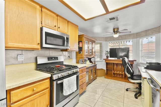 kitchen featuring light tile patterned flooring, stainless steel appliances, backsplash, a textured ceiling, and ceiling fan