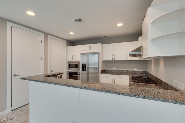 4525 Dean Martin Dr Unit 2704, Las Vegas, NV 89103 - kitchen with appliances with stainless steel finishes, wall chimney exhaust hood, dark stone countertops, a peninsula, and recessed lighting