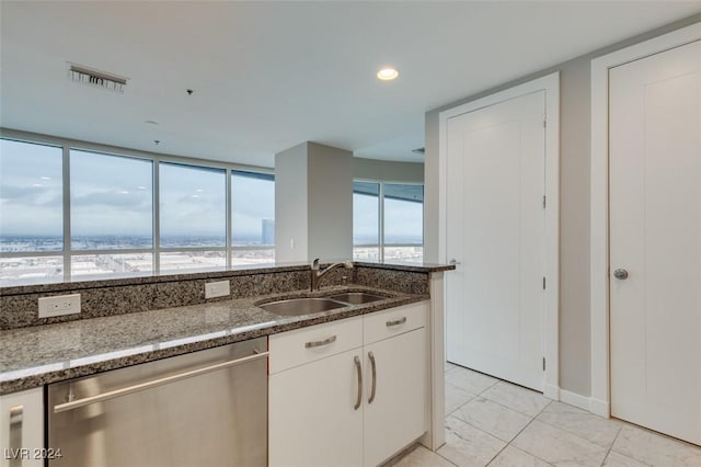 4525 Dean Martin Dr Unit 2704, Las Vegas, NV 89103 - kitchen with dishwasher, a sink, dark stone counters, white cabinets, and baseboards