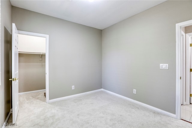 unfurnished bedroom featuring light carpet, a closet, and a spacious closet