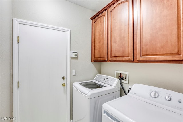 clothes washing area with cabinets and washer and dryer