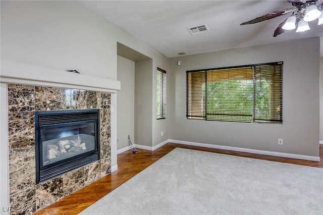 living room with ceiling fan, dark hardwood / wood-style floors, and a tiled fireplace