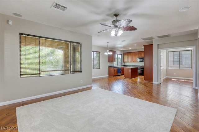 kitchen featuring hardwood / wood-style flooring, black appliances, ceiling fan with notable chandelier, a center island, and pendant lighting