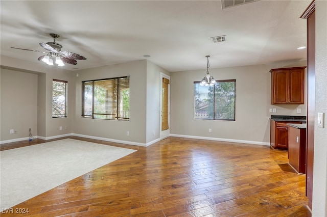 interior space featuring ceiling fan with notable chandelier and hardwood / wood-style flooring