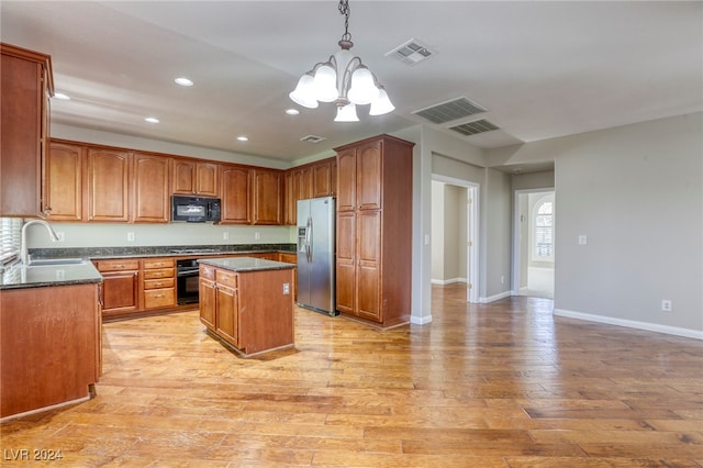 kitchen featuring black appliances, sink, light hardwood / wood-style floors, a chandelier, and a center island