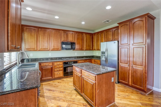 kitchen featuring light wood-type flooring, sink, black appliances, and a center island