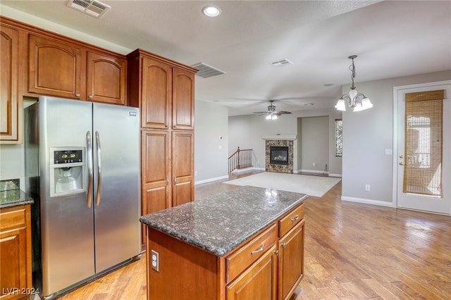 kitchen with a kitchen island, light wood-type flooring, hanging light fixtures, and stainless steel fridge with ice dispenser