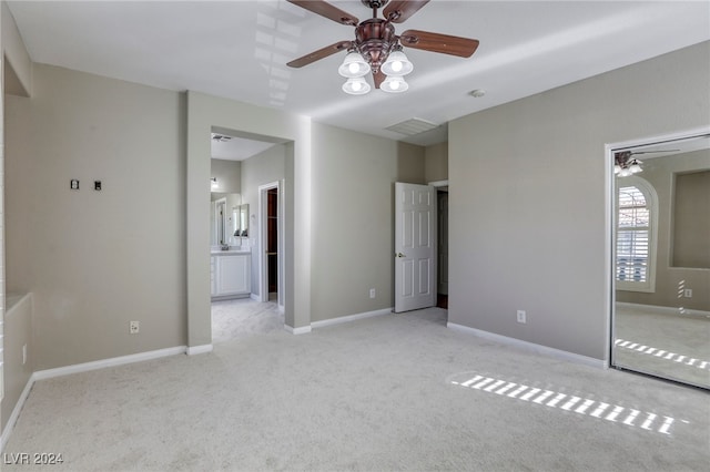 unfurnished bedroom featuring connected bathroom, light carpet, and ceiling fan