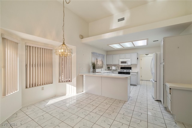 kitchen featuring kitchen peninsula, white appliances, pendant lighting, sink, and a skylight