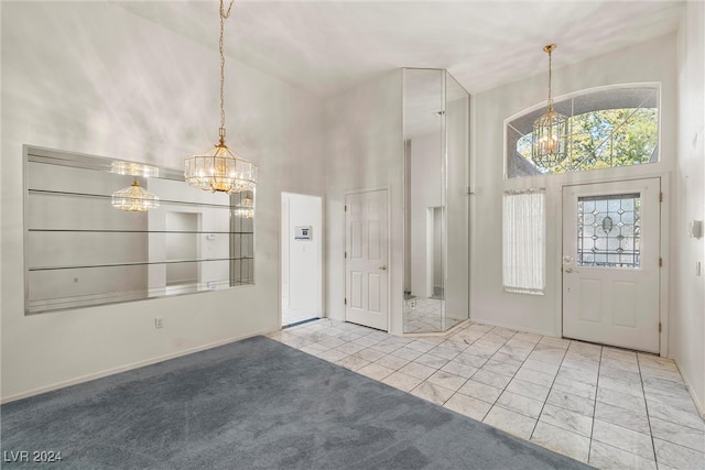 foyer entrance featuring a chandelier, light carpet, and a towering ceiling