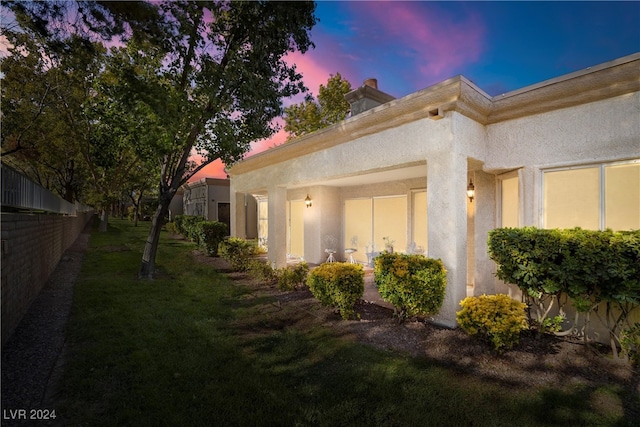 property exterior at dusk with a lawn