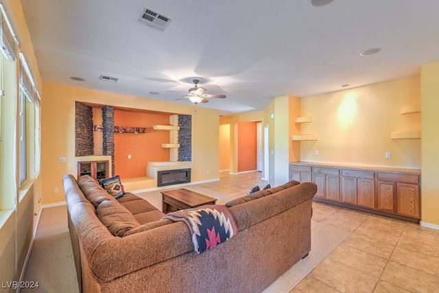 living room featuring a wood stove, ceiling fan, and light tile patterned floors