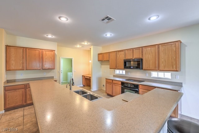 kitchen with kitchen peninsula, black appliances, sink, light tile patterned floors, and a breakfast bar