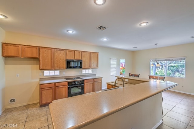 kitchen featuring black appliances, light tile patterned flooring, pendant lighting, sink, and a chandelier