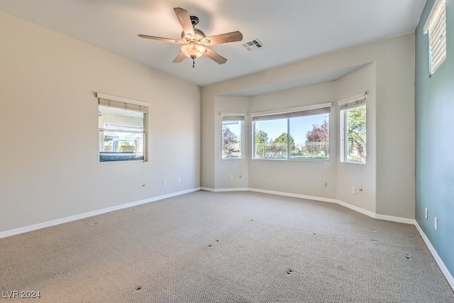 carpeted empty room featuring a wealth of natural light and ceiling fan