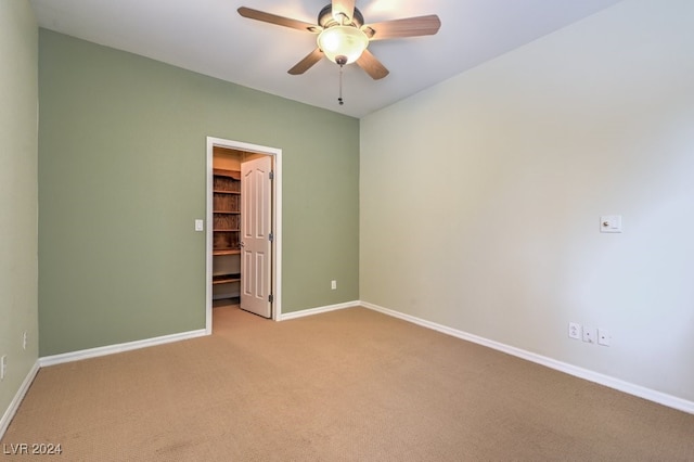 unfurnished bedroom featuring ceiling fan, a closet, a walk in closet, and light colored carpet