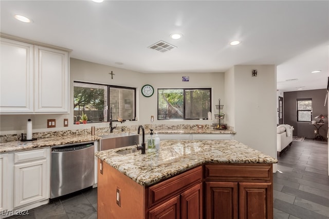 kitchen featuring light stone counters, stainless steel dishwasher, a kitchen island with sink, sink, and white cabinetry