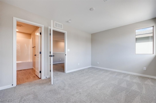 unfurnished bedroom featuring ensuite bath and light colored carpet