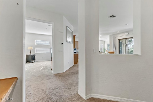 hall featuring a wealth of natural light and light colored carpet