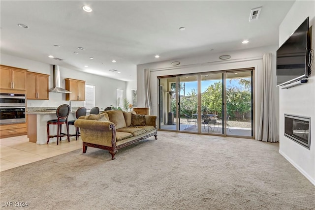 living area featuring recessed lighting, visible vents, a glass covered fireplace, light carpet, and light tile patterned flooring