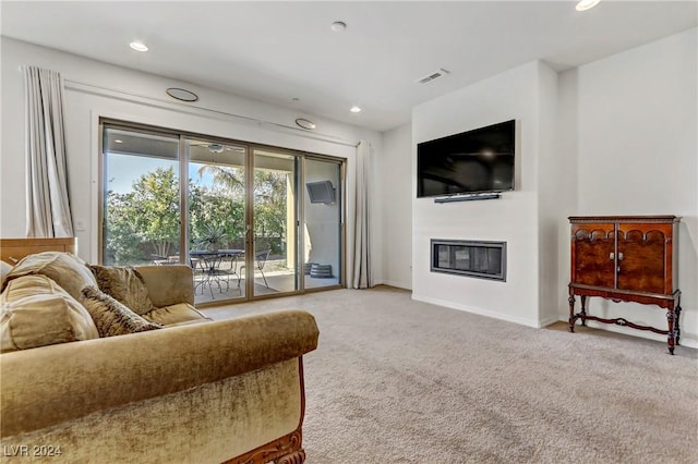 carpeted living room with a glass covered fireplace, visible vents, baseboards, and recessed lighting