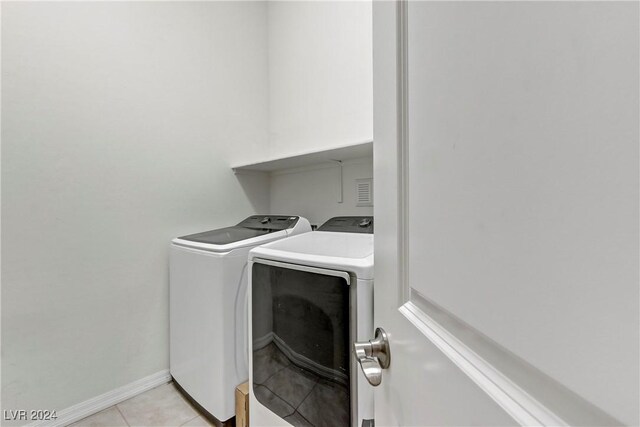 washroom featuring washing machine and dryer and light tile patterned floors