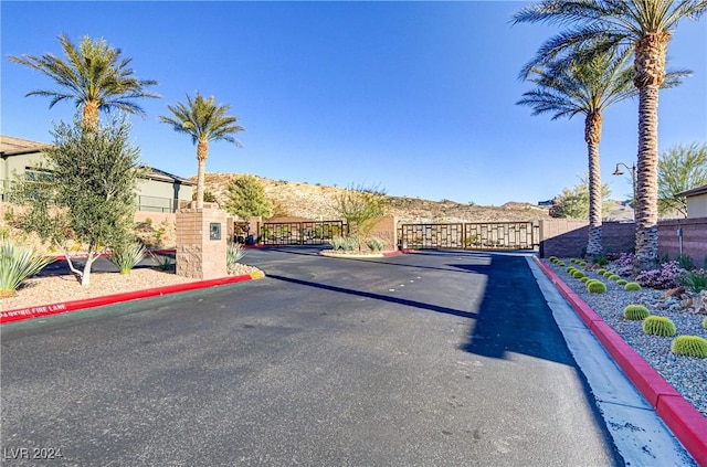 view of street featuring a gate, curbs, and a gated entry