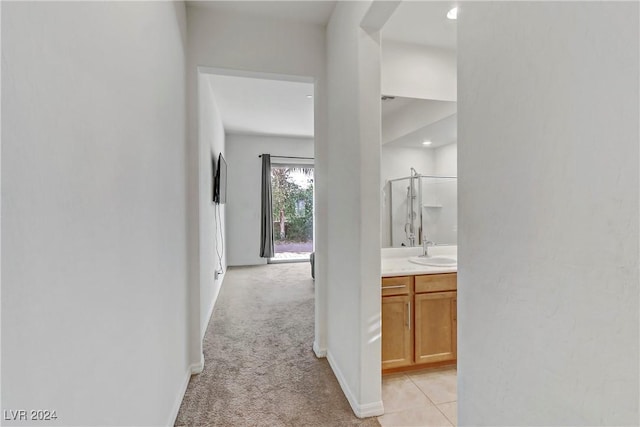 hallway with light colored carpet, a sink, and baseboards