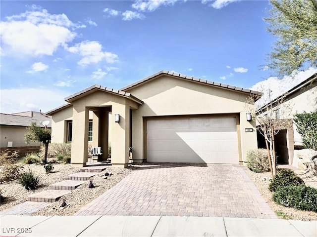 ranch-style house featuring a garage, decorative driveway, and stucco siding