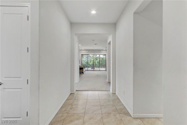 hallway featuring light carpet, recessed lighting, baseboards, and light tile patterned flooring