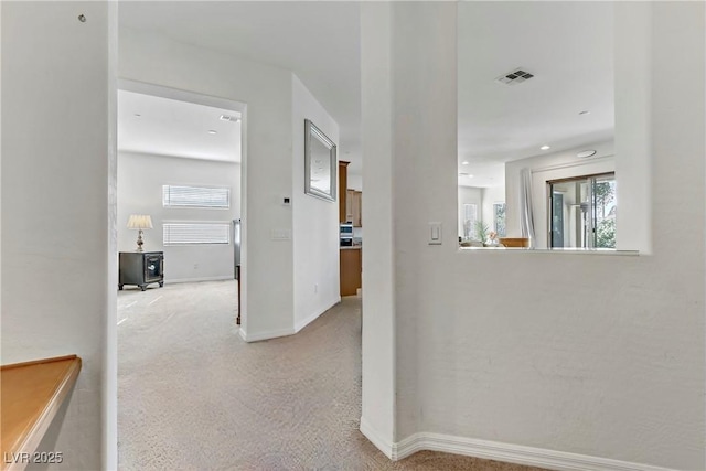 hall featuring a healthy amount of sunlight, carpet, baseboards, and visible vents