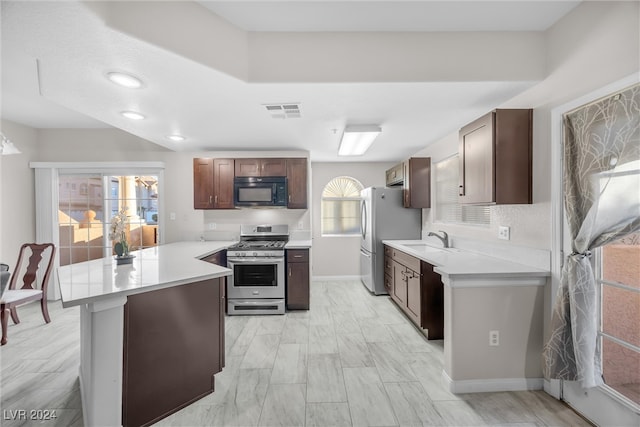 kitchen with kitchen peninsula, sink, dark brown cabinetry, and appliances with stainless steel finishes