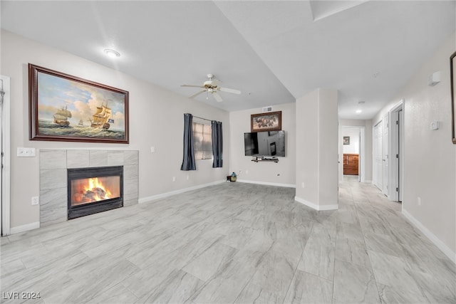 unfurnished living room with a tiled fireplace and ceiling fan