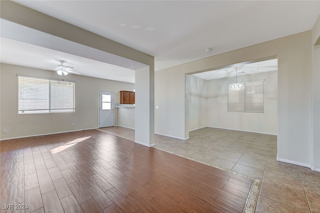 spare room with ceiling fan with notable chandelier and light hardwood / wood-style floors